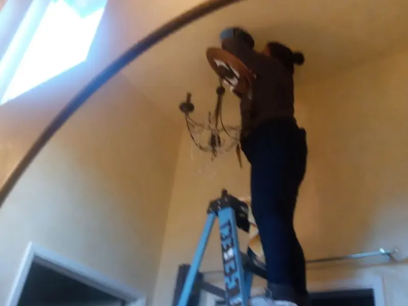 Electrician installing a chandelier in a Coalinga residence